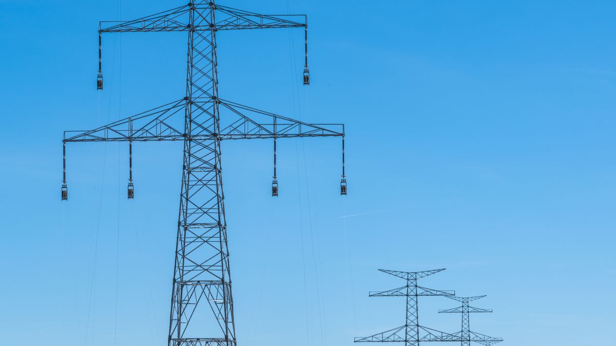 青空の下、田園地帯に並ぶ送電鉄塔